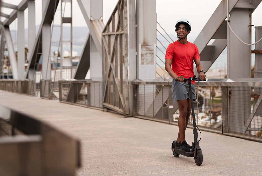 man riding xiaomi electric scooter on a bridge