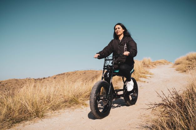 girl riding a super73 on a path with dry grass around